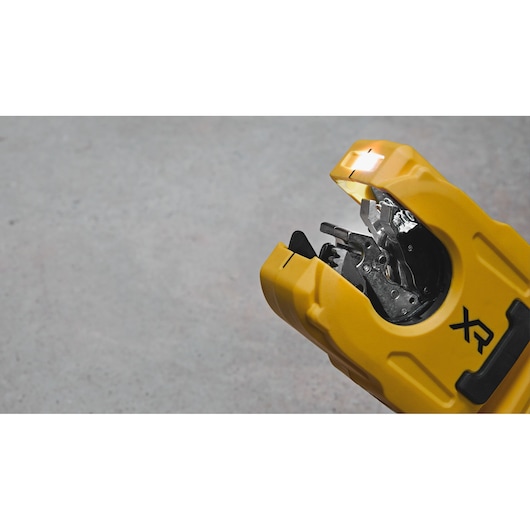 Close-up of a DEWALT DCE154N wire stripping tool with yellow casing and visible internal metal components, shown against a concrete background.