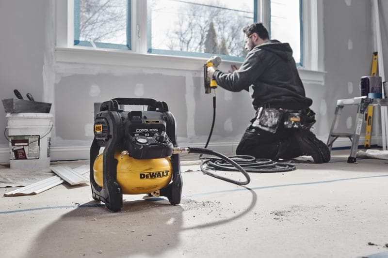 Compressore senza fili DEWALT in stanza rinnovata, operaio usa sparachiodi vicino alla finestra.