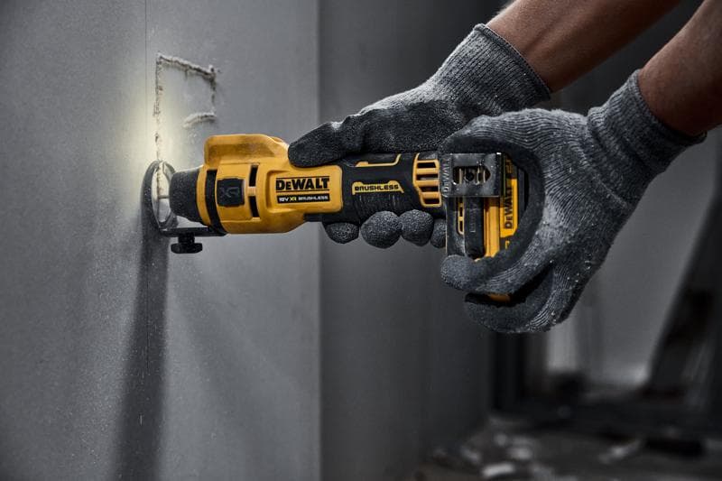 Utensile rotante DEWALT senza fili taglia cartongesso, usato da mani con guanti.