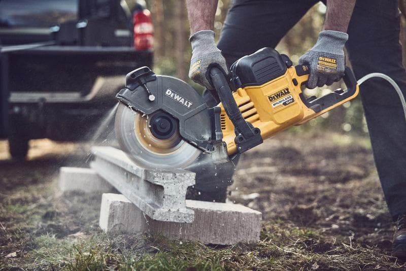 Sega DEWALT taglia il cemento all'aperto, operatore con guanti protettivi.