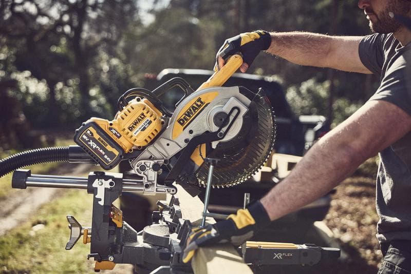 Persona usa una troncatrice a batteria DEWALT per tagliare legno all'aperto, strumento giallo-nero XR FLEXVOLT.