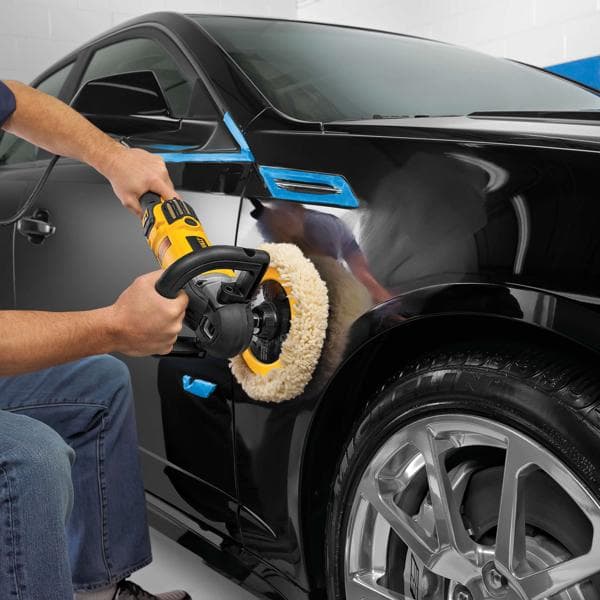 Persona lucida il parafango di un’auto nera con lucidatrice DEWALT in garage.