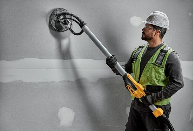 Operaio usa DEWALT DWE7800, DWE7800-QS levigatrice su parete in cartongesso. Prodotto fotografico.