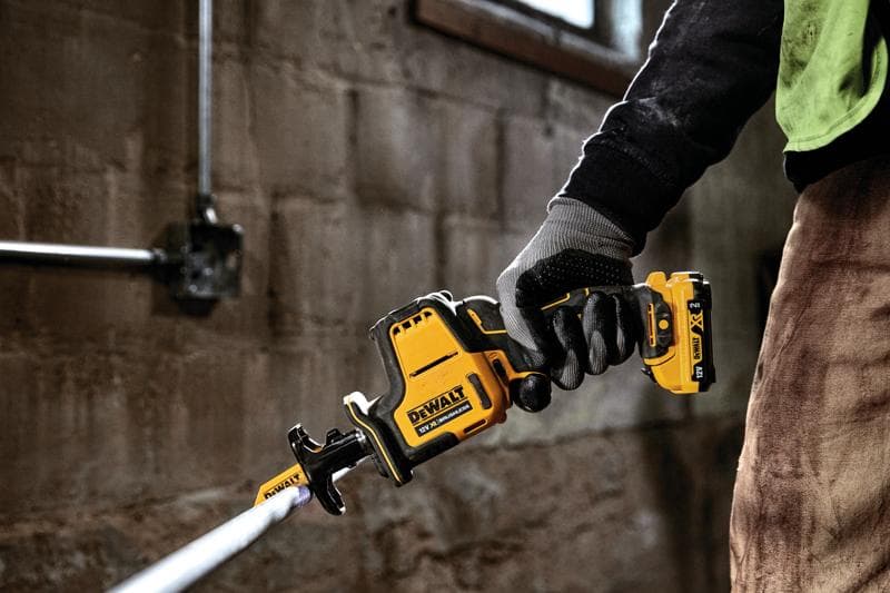 Mano con guanto usa un seghetto alternativo DEWALT a batteria per tagliare un tubo.
