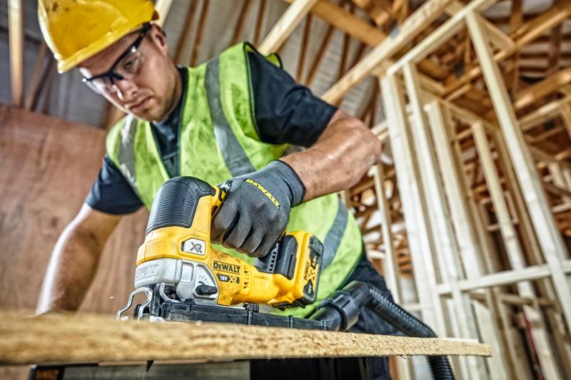 Seghetto DEWALT DCS334P2 taglia legno in cantiere, operatore con abbigliamento di sicurezza.