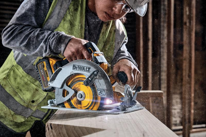 Sega circolare DEWALT a batteria taglia legno, usata da un operaio con gilet in cantiere.