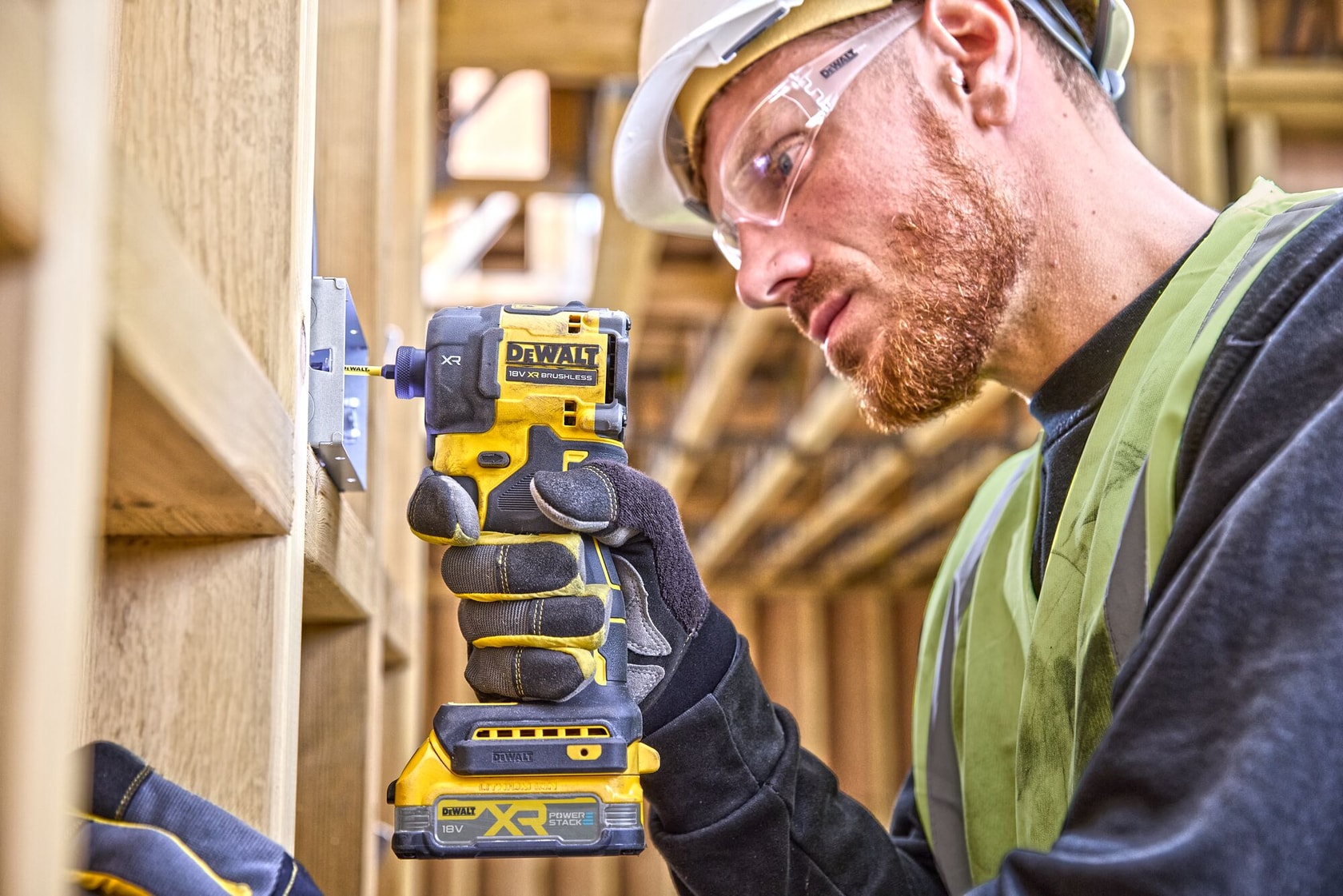 Operaio usa un avvitatore a impulsi DEWALT DCF870NT su struttura in legno in cantiere.