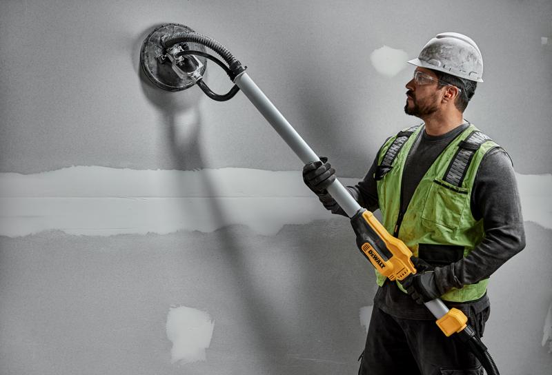 Operaio usa DEWALT DWE7800, DWE7800-QS levigatrice su parete in cartongesso. Prodotto fotografico.